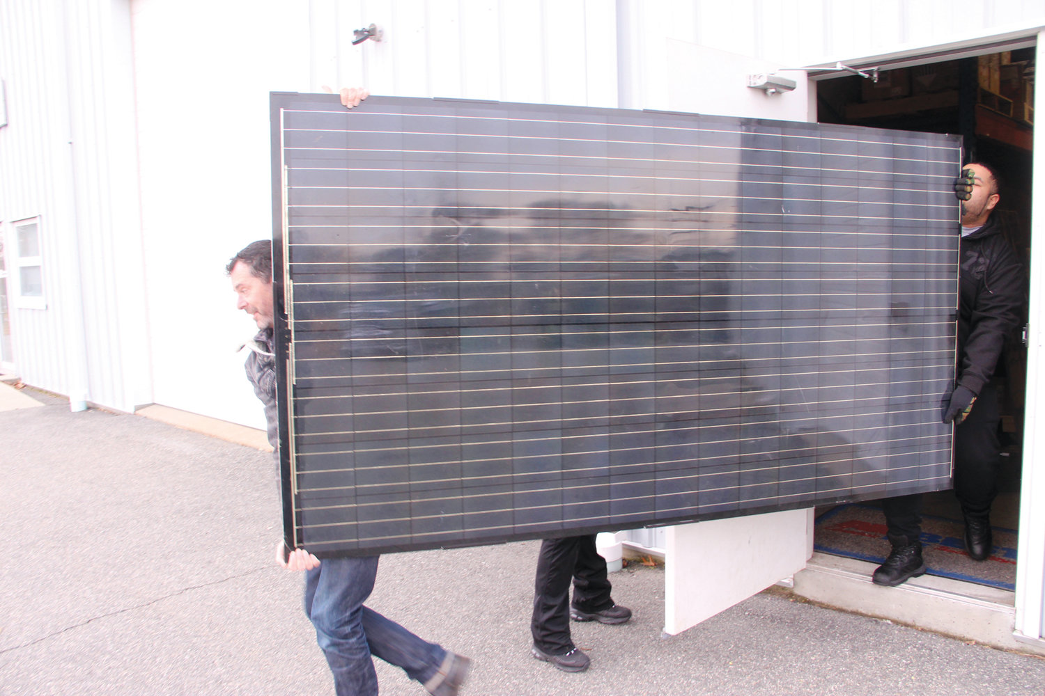 EARLY MODEL: eNow employees move a truck solar panel, which is about the size of those being installed on 33 RIPTA buses. The bus panels weigh 19 pounds and are flexible.